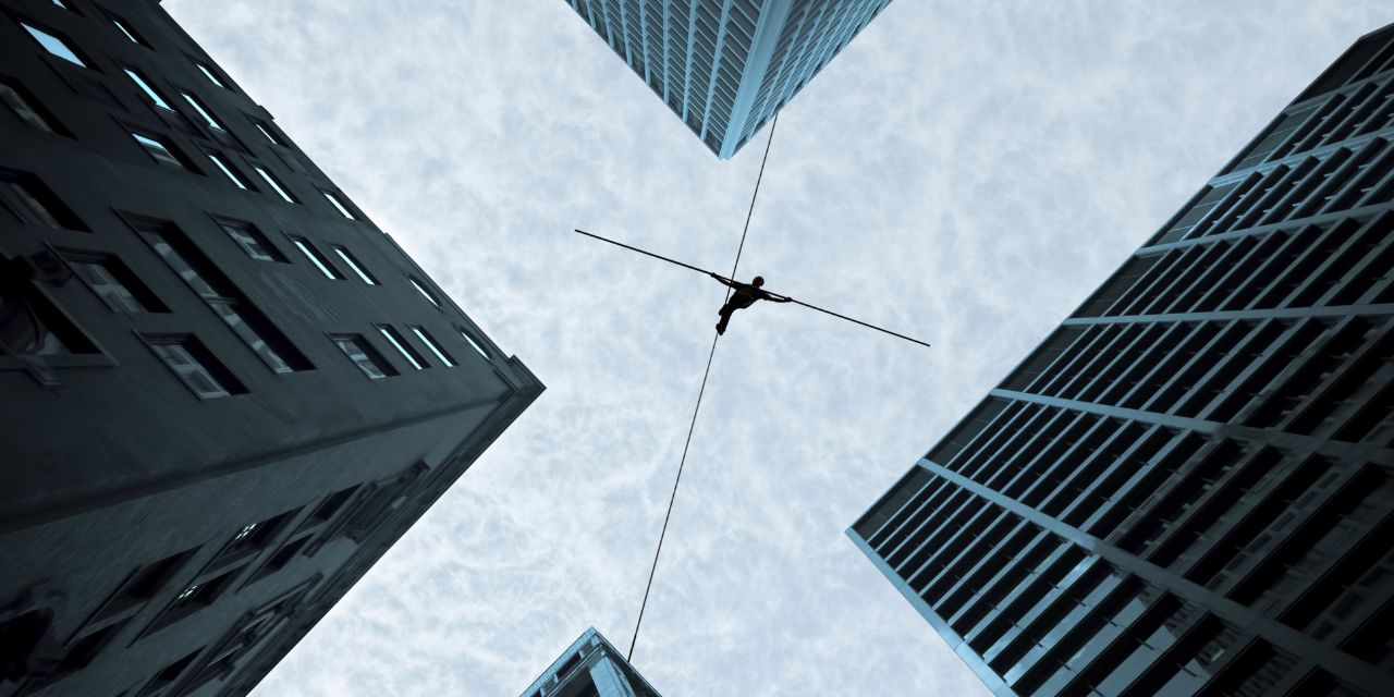 an acrobat walking on the line between buildings