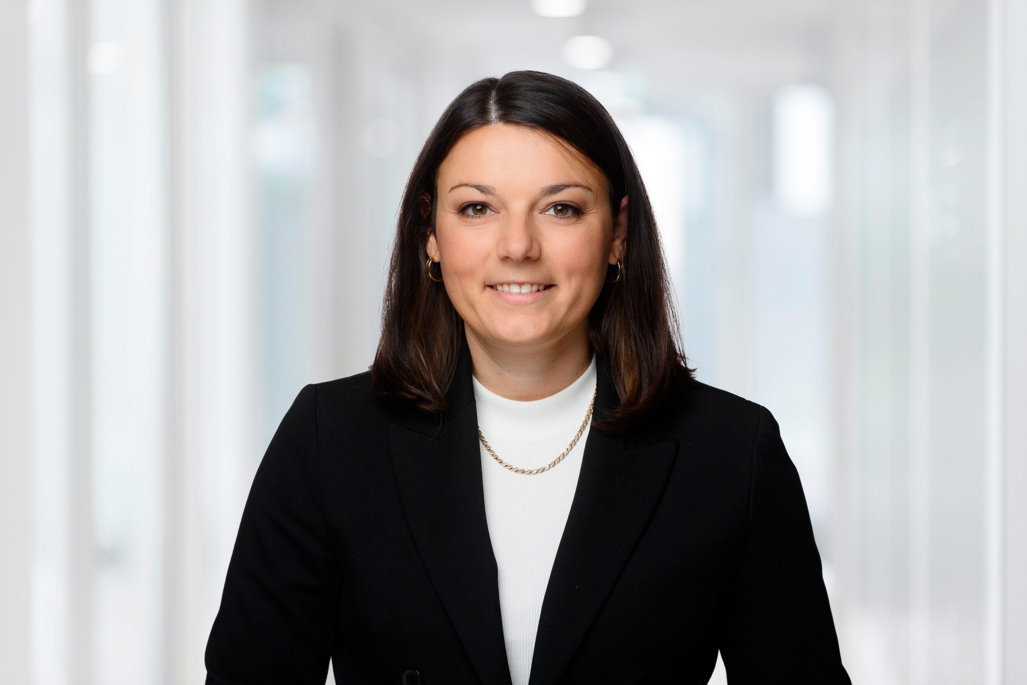 Das Bild zeigt Maria Herrmann, Head of Home Operations in der CEE Region. Sie hat dunkelbraune lange Haare, lächelt in die Kamera und trägt einen schwarzen Blazer über einem weißen Oberteil. Außerdem trägt sie eine Goldkette.