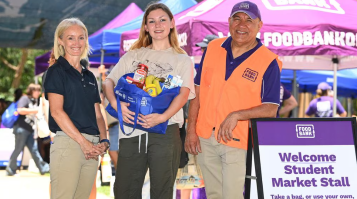 Three people smiling to camera at market stall