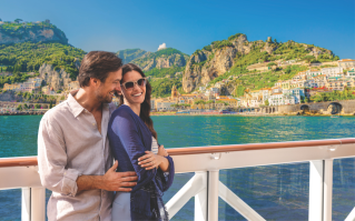 A mean and woman leaning their backs against a cruise railing