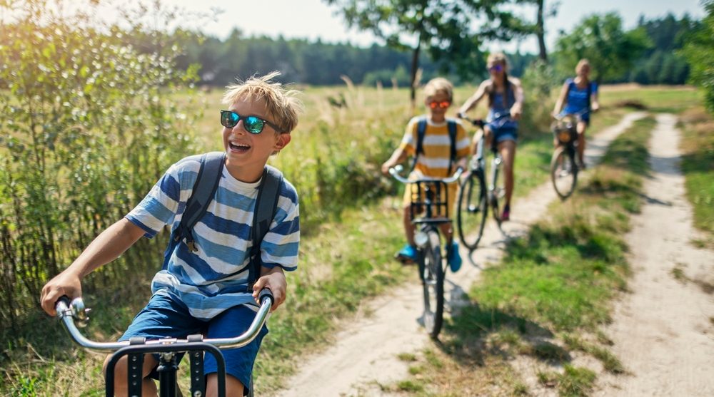 Kids riding on bikes through an off the beaten path - looking carefree and happy