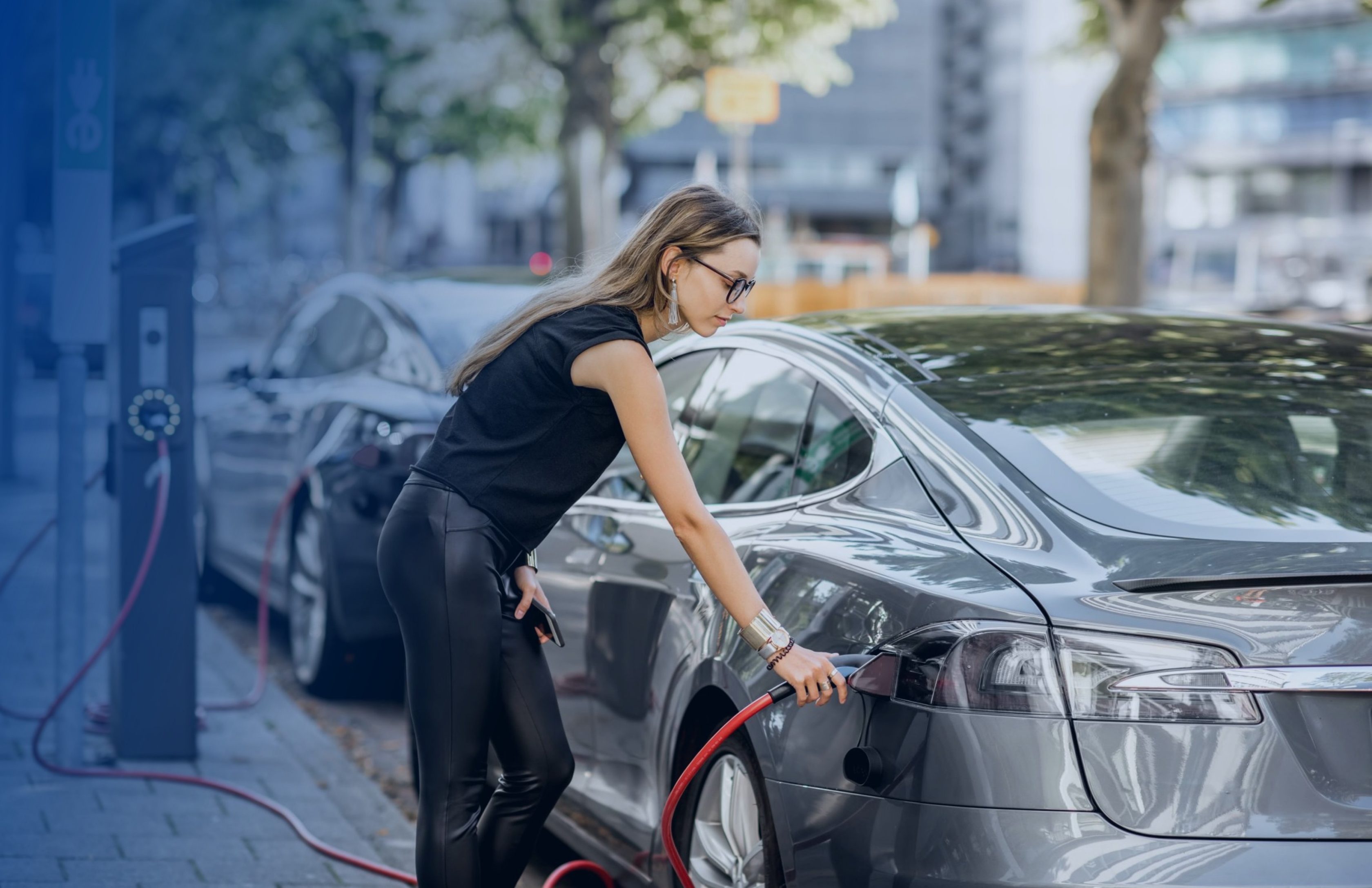 Jeune femme branchant sa voiture électrique à une borne de recharge