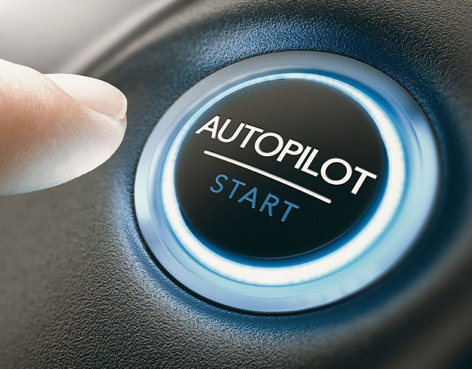 Nahaufnahme eines Fingers, der eine leuchtende Autopilot-Starttaste drückt – Symbol für autonome Fahrtechnik.