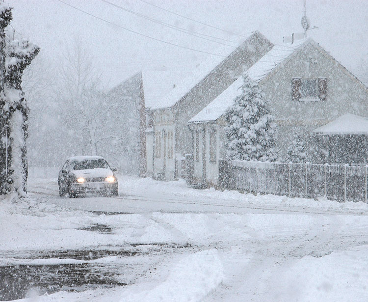 Stark beschneite Straße in Ortschaft 
