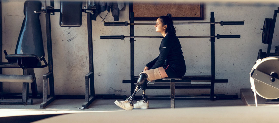 Para-athletin mit Prothesen an beiden Beinen beim Training im Fitnessraum