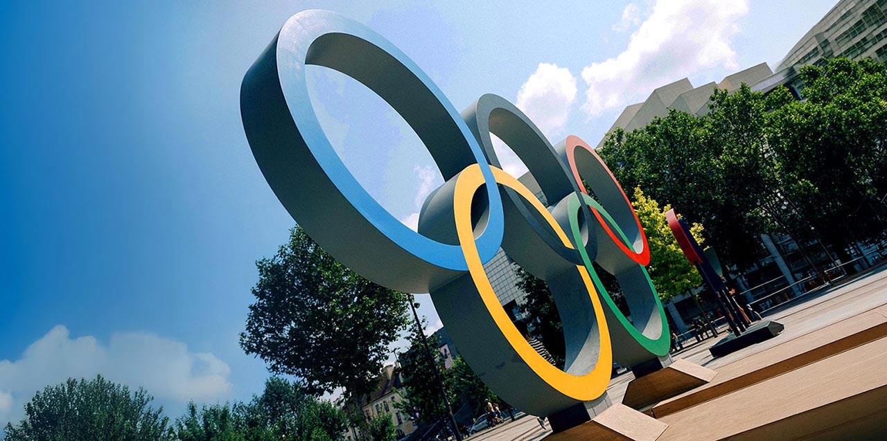 Olympic rings sculpture outdoors in a city setting, symbolizing the Olympic and Paralympic Movements and their global partnership with Allianz as an insurance partner.