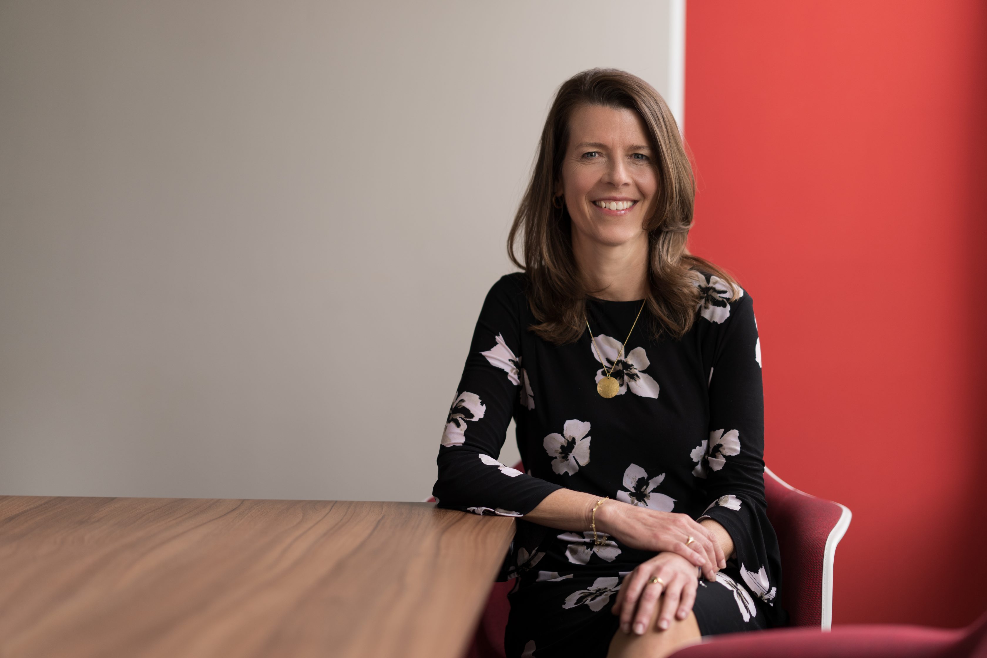 Photograph of Barbara Karuth-Zelle seated at a desk, adorned with a warm smile