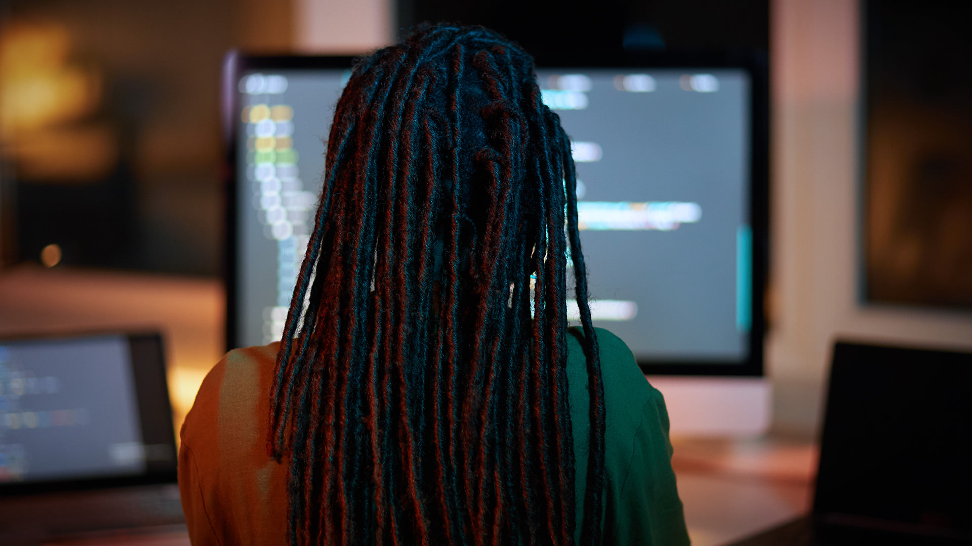 Woman with long dreadlocks working at a computer screen in an office.