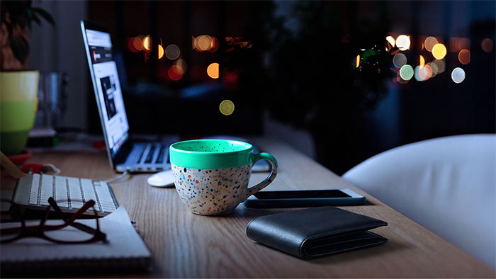 Laptop, coffee mug, smartphone and wallet on a desk at night - representing finances, work and financial concerns.
