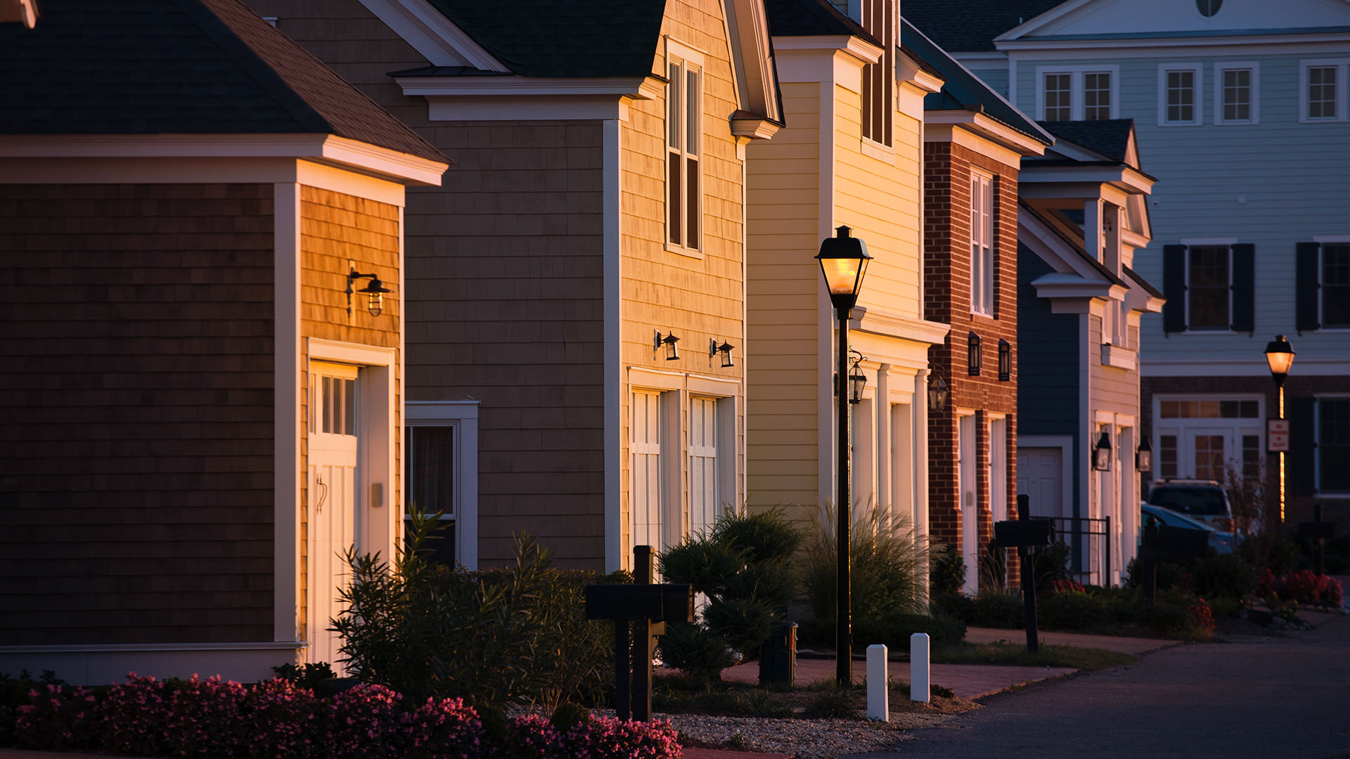 Residential street with houses at sunset, warm light on facades.