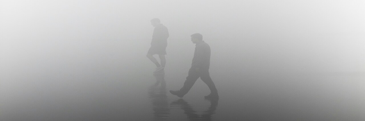 image of two people walking in fog