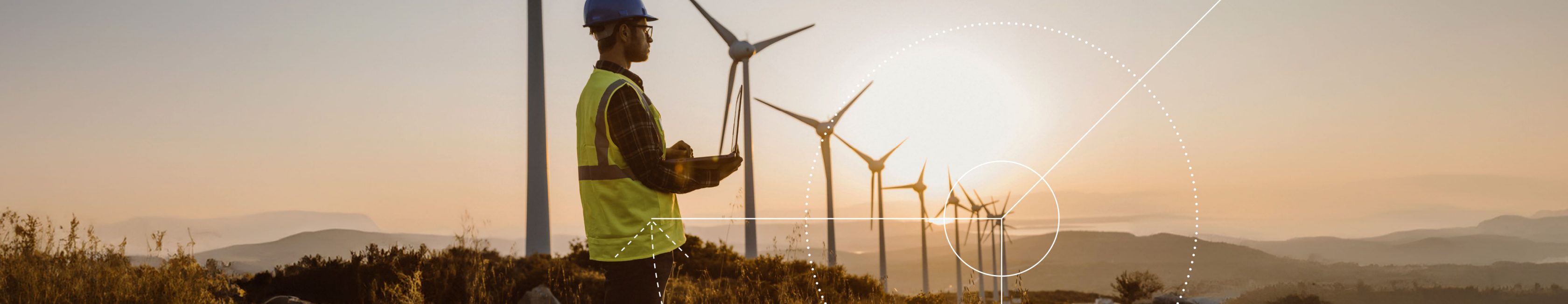 Wind turbine specialist with laptop in beautiful hilly landscape in front of a row of wind turbines in evening mood