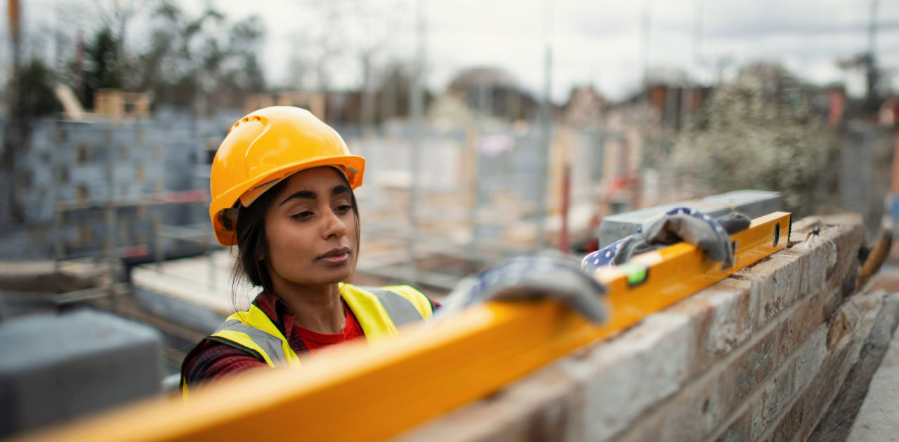  Female worker wearing a yellow safety helmet on a large construction site