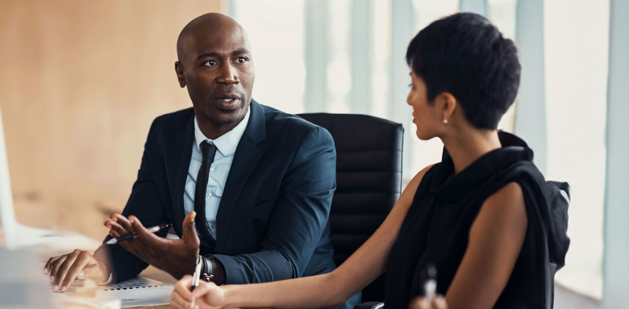 Business partners (a woman and a man) having a lively conversation at a conference table.