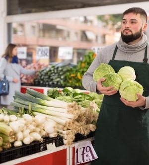 Imagen de hombre reponiendo verduras en su tienda