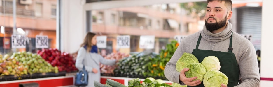 Imagen de un hombre colocando verduras en su tienda
