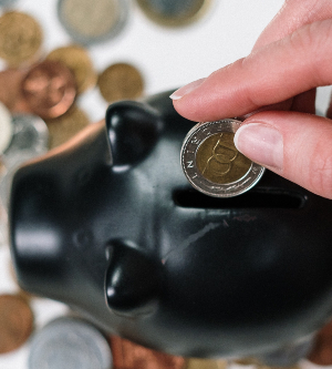 Imagen de una persona metiendo dinero en una hucha de cerdito