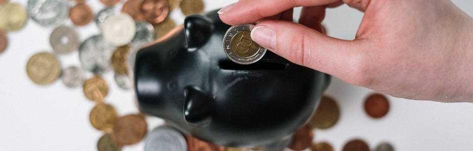 Imagen de una persona metiendo dinero en una hucha de cerdito