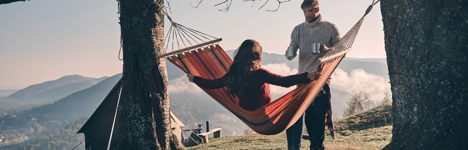 Imagen de hermosa joven manteniendo los brazos extendidos mientras se relaja en una hamaca al aire libre