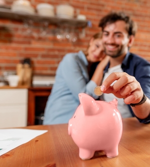 Imagen de una pareja metiendo dinero en hucha cerdito de color rosa