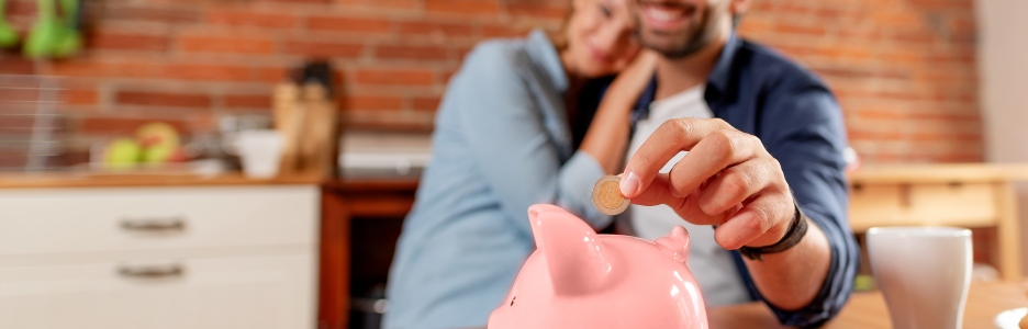 Imagen de una pareja metiendo dinero en hucha cerdito de color rosa