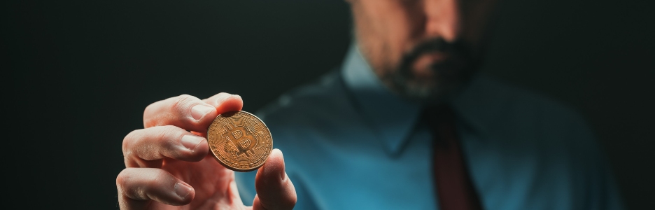 Imagen de un hombre con una moneda Bitcoin en su mano
