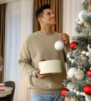 Imagen de un hombre decorando su arbol de Navidad