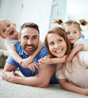 Imagen de una familia jugando encima de la alfombra de su salón