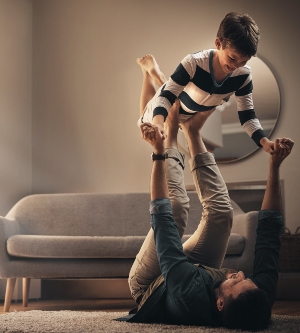 Imagen de un padre jugando con su hijo en el salón de la casa