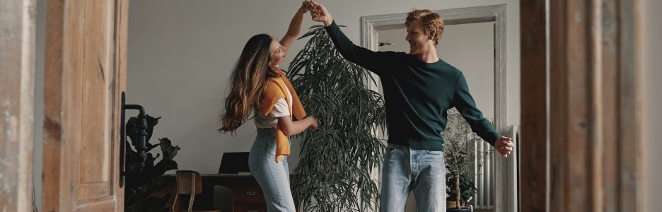 Imagen de longitud total de una pareja joven despreocupada bailando juntos en casa.