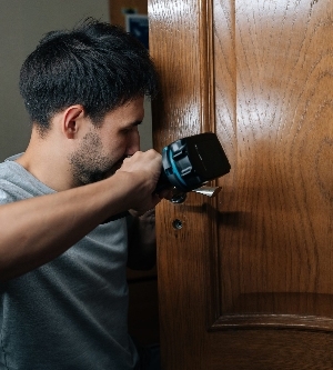 Imagen de un hombre arreglando la cerradura de una puerta de una casa