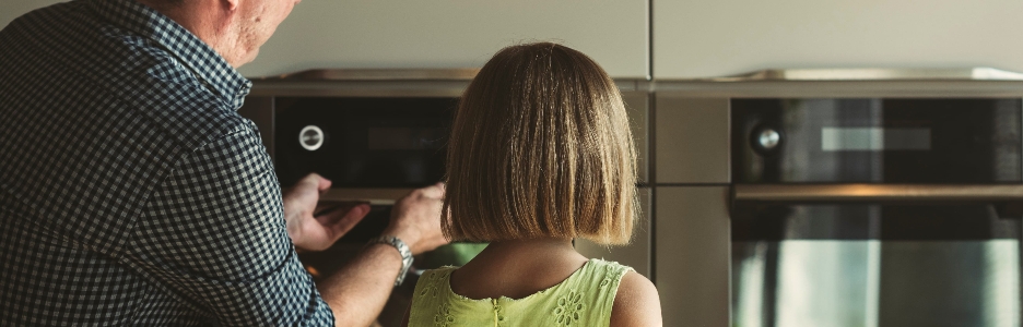 Imagen de niña con su abuelo mirando las galletas de la hornada