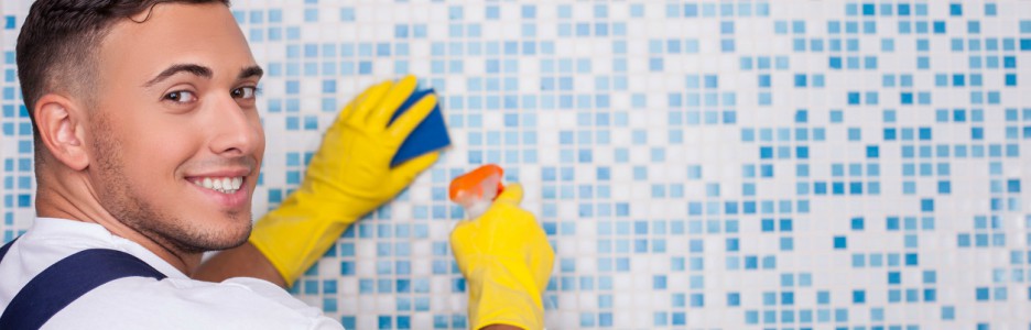 Imagen de un hombre limpiando los azulejos del baño