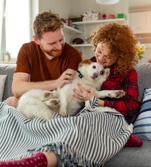 Imagen de una pareja jugando con un perro