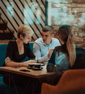 Imagen de empresarios felices sonriendo con entusiasmo durante una reunión en una cafetería. Un grupo de profesionales de negocios exitosos trabajando en equipo en un entorno laboral multicultural