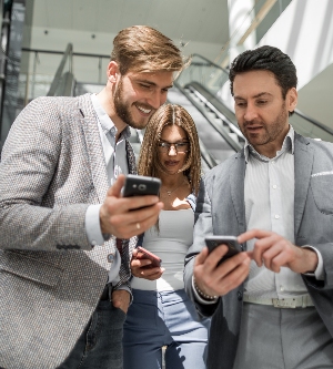 Imagen de un grupo de jóvenes empresarios mirando las pantallas de sus teléfonos inteligentes