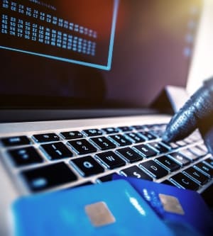 Imagen de tarjetas de crédito Robo Concepto. Hacker con tarjetas de crédito en su computadora portátil usarlos para compras no autorizadas. Los pagos no autorizados.