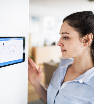 Imagen de una mujer controlando el sistema inteligente de su hogar utilizando una pantalla táctil
