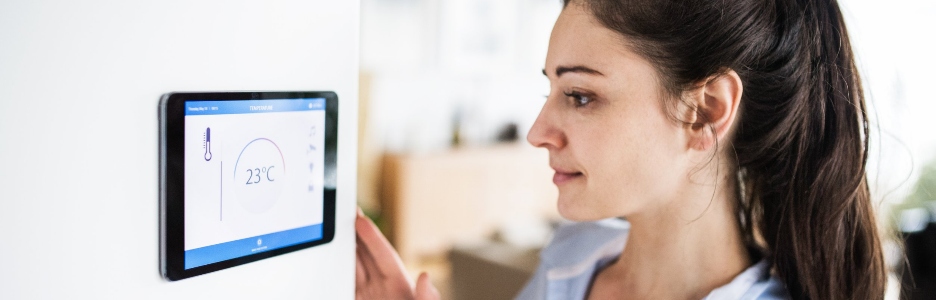 Imagen de una mujer controlando el sistema inteligente de su hogar utilizando una pantalla táctil