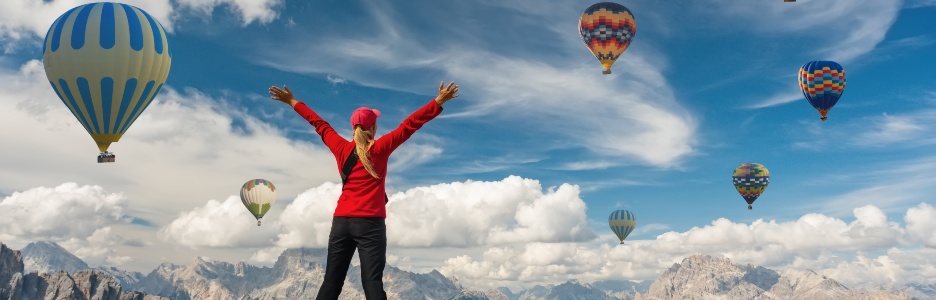 Imagen de una persona saludando a los globos aerostáticos en la montaña