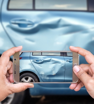 Imagen de una persona haciendo una foto con su móvil de su coche para cobrar una indemnización
