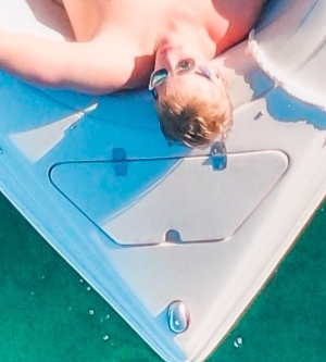 Imagen de un hombre tumbado en su barco tomando el sol