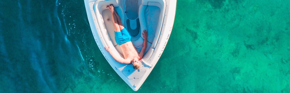 Imagen de un hombre tumbado en su barco tomando el sol