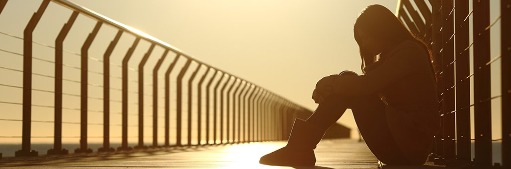 Imagen de una mujer sentada sobre un puente llorando