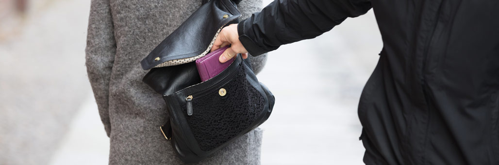 Imagen de una persona robando una cartera del bolso de una mujer