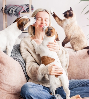Imagen de una mujer jugando con sus perros y gatos en el salón de su casa