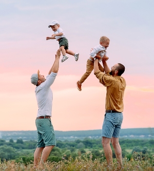Imagen de dos padres jugando con sus hijos en el campo
