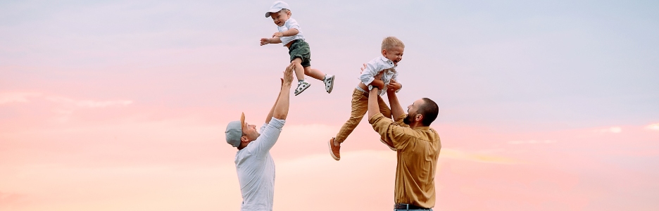 Imagen de dos padres jugando con sus hijos en el campo