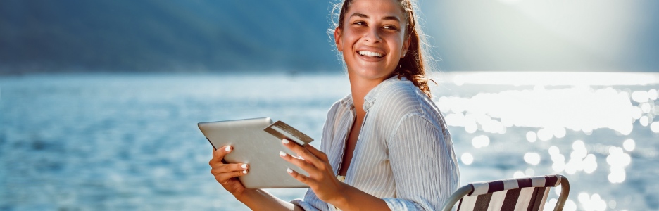 Imagen de una mujer sonriendo haciendo una compra online con su tarjeta bancaria