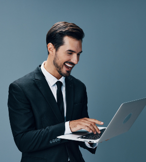 Imagen de un hombre en traje felizmente navegando por internet en su ordenador portátil